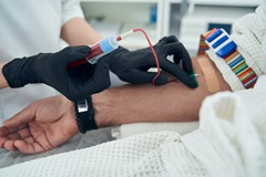 Medical laboratory worker taking blood sample from patient